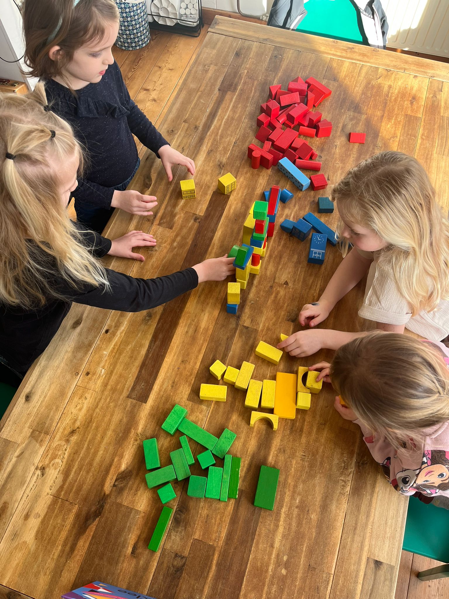 Jonge kinderen bouwen geconcentreerd met kleurrijke materialen tijdens het Mini Makers programma bij INKAMI Creative Studio