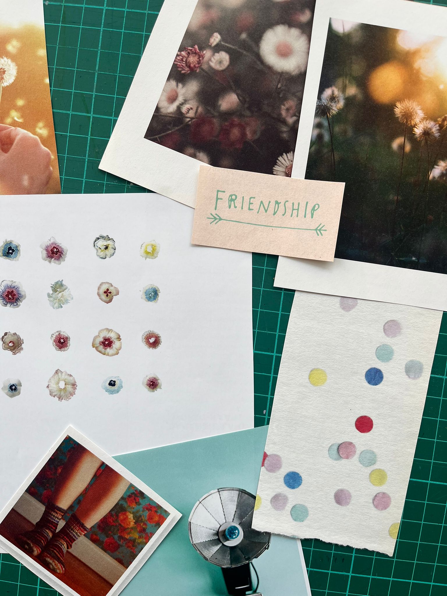 Grafische compositie van handgemaakte kaarten met bloemenprints, kleurrijke stippen en een handgeschreven Friendship label op een groene snijmat tijdens een workshop bij INKAMI Creative Studio in Den Helder 